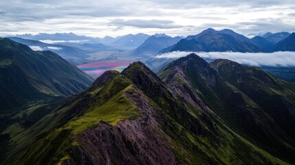 Fototapeta premium Aerial view of majestic mountainous landscape with vibrant fields and cloudy sky in background