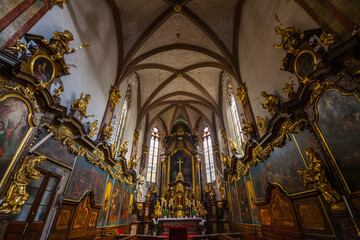 Obraz premium Interior view of a church featuring a high-ceilinged nave with arched vaults, ornate golden decorations, and a central altar, viewed from a slightly elevated perspective
