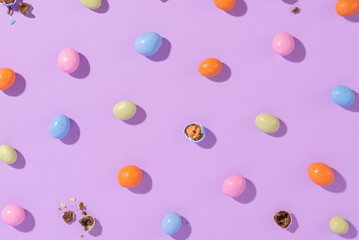 Colorful easter dragee on a violet background. Multicolored candies in the shape of eggs covered with glaze