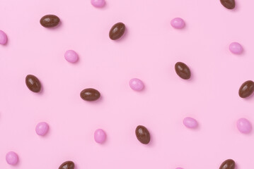 Pink easter dragee on a pink background. Sweet candies in the shape of eggs covered with pink glaze