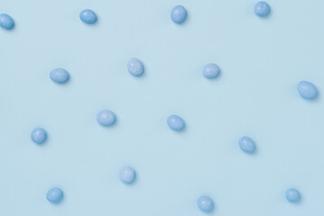 Blue easter dragee on a blue background. Sweet candies in the shape of eggs covered with blue glaze