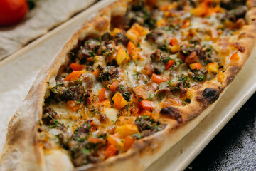Turkish pide with minced meat, vegetables and cheese on a plate in a stylish restaurant setting