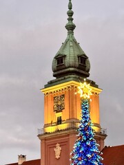 Obraz premium view of the large illuminated christmas tree in front of the royal castle in the old town of warsaw on a december evening 