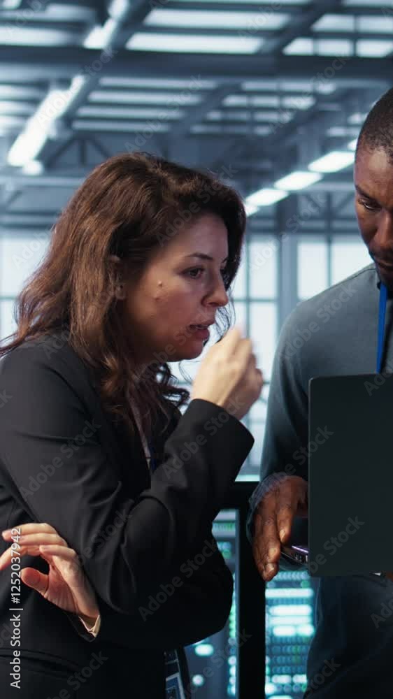Poster vertical video developers in data center workspace coding on laptop, analyzing metrics, optimizing s