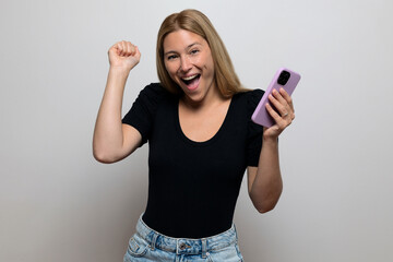 Excited blonde woman smiling, holding her phone