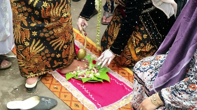 The traditional Javanese wedding procession called "Temu Manten". The bride washes the groom's feet with water mixed flowers. Sacred event of traditions of Indonesian wedding rituals