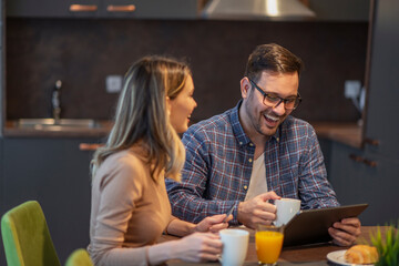 Happy Couple Enjoying Breakfast and Tablet in Modern Kitchen