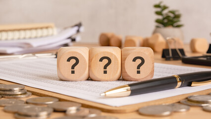 wooden blocks with question marks on financial documents, symbolizing business risks and uncertainty