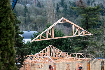 New home under construction in framing phase, roof trusses being delivered and hoisted up to roof...
