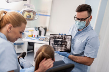 Dentist Discussing X-Ray Results With Patient In Clinic
