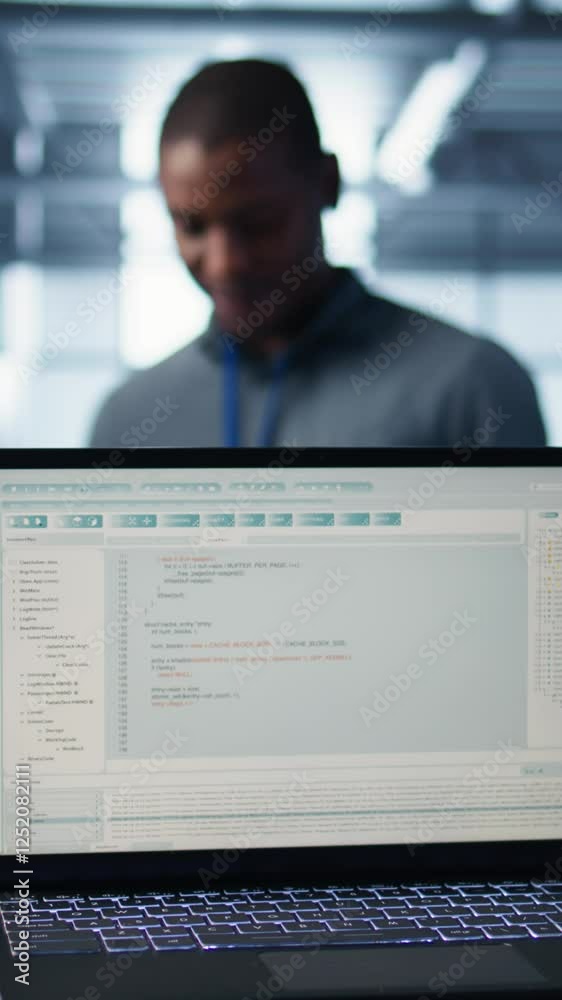 Poster vertical video lines of code on laptop display used by teamworking data center colleagues to run sec