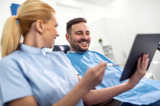 Smiling Patient At Dentist Reviewing X-rays On Tablet