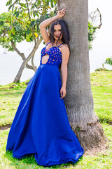 
Beautiful young Peruvian Hispanic woman, modeling a blue dress, with different posture against, next to the sea, on a path, between houses.