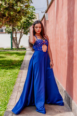 
Beautiful young Peruvian Hispanic woman, modeling a blue dress, with different posture against, next to the sea, on a path, between houses.