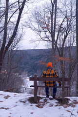 Man on Bench in Winter enjoying the view of a frozen river
