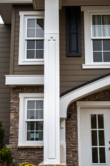 Modern House Exterior: Elegant Stone and Brown Facade with White Columns and Windows. Real Estate Photography