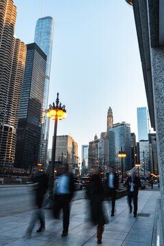 Chicago downtown, motion blur of people walking on city streets, modern skyscrapers, urban life, financial district, corporate hustle, golden hour, busy pedestrians, business district, fast-paced city
