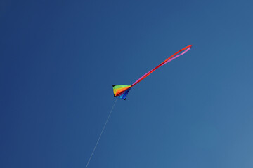 One colorful kite flying in blue sky