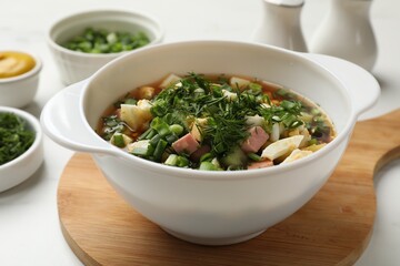 Delicious okroshka soup and ingredients on white table, closeup