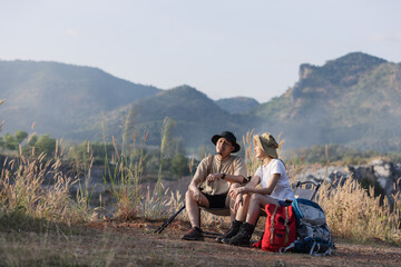 Fototapeta premium A couple takes a break during their hike, sitting on a trail with a scenic mountain view. 