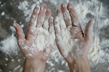 Fototapeta premium Close-up view of baker's hands covered in white flour during food preparation