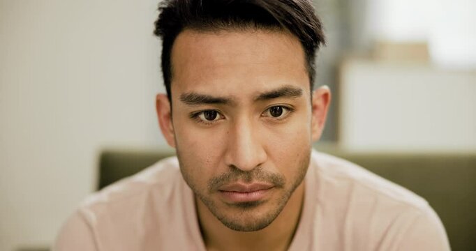Asian man, thinking and depression in home with mental health, anxiety and process trauma on sofa. Person, worry and closeup on face with stress from memory on couch in living room and apartment