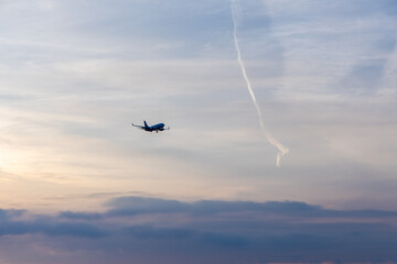 Airplane Flying Against Scenic Sunset Sky with Contrail in Background
