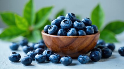 A wooden bowl overflowing with plump, juicy blueberries, surrounded by more berries and vibrant green leaves, evokes a sense of freshness and natural abundance.