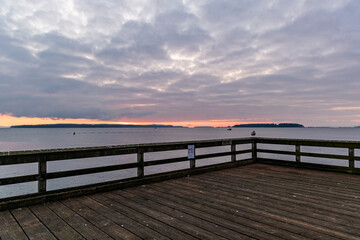 Obraz premium Calm Coastal Pier Overlooking the Ocean at Sunset with Cloudy Skies
