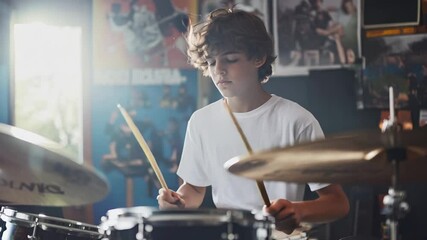 A focused teenage boy plays the drums in a music room decorated with band posters and vintage memorabilia. The warm lighting and creative atmosphere reflect his passion for music and dedication 
