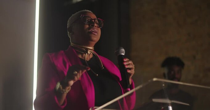 African descent woman passionately preaching during evangelical church service, holding microphone, delivering sermon, powerful expression, spiritual leadership, guiding congregation