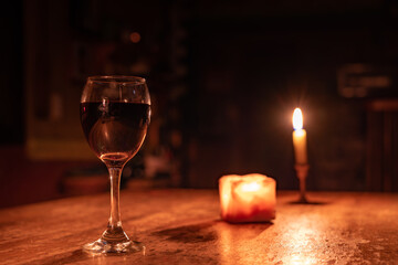 A glass of wine is on a table with candles Romantic Valentine's Day evening. Defocused Lights Background