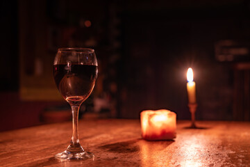 A glass of wine is on a table with candles Romantic Valentine's Day evening. Defocused Lights Background