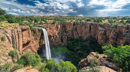 Waterfall cascading down canyon cliffs, scenic landscape, dramatic sky, nature background, travel photography