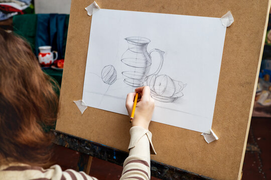 Girl artist in art studio drawing pencil sketch on easel. 