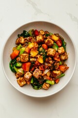 Tofu and vegetable stir-fry with sauce, served in a bowl on a marble surface