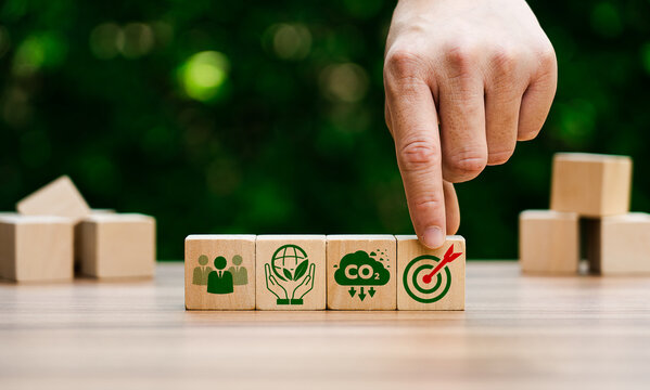 Hand Arranging Wooden Blocks Representing Sustainability Goals, Carbon Reduction, Environmental Responsibility, and Target Achievement in Green Business Strategy
