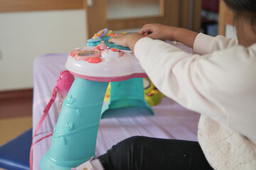 Child exploring colorful play table with various activities in room