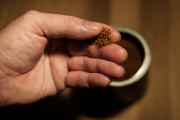 Barista hand holding freeze dried coffee granules above filter