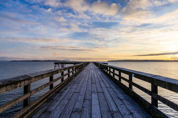 Obraz premium Scenic Wood Pier at Sunset Overlooking Calm Ocean Waters and Distant Islands