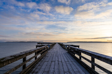 Obraz premium Picturesque Pier at Sunrise Over Tranquil Waters and Vibrant Sky
