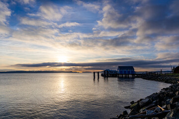 Obraz premium Sunrise Over the Ocean with a Dock and a Coastal Landscape