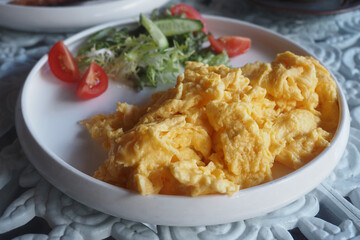 Soft scrambled eggs served with fresh vegetables on a plate