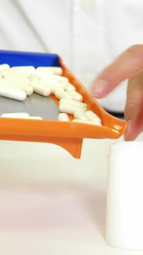 Pharmacist putting pill in container at pharmacy