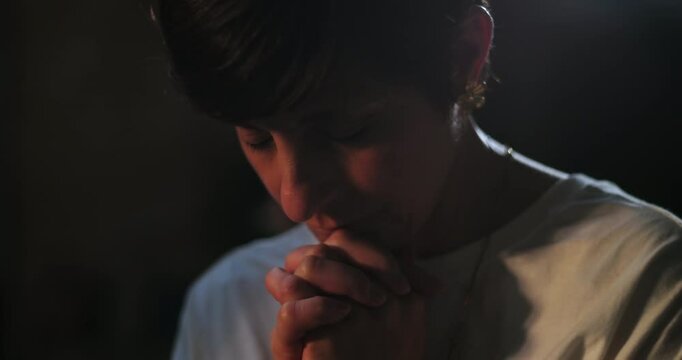 Woman bowing head in prayer, hands clasped in silent spiritual reflection, peaceful worship moment, serene focus on inner faith and connection to devotion