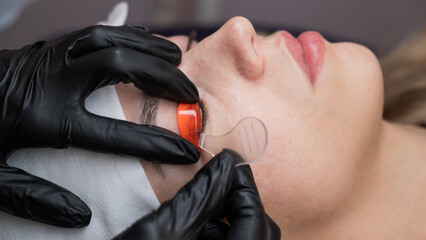 Caucasian woman undergoing eyelash lamination procedure. 
