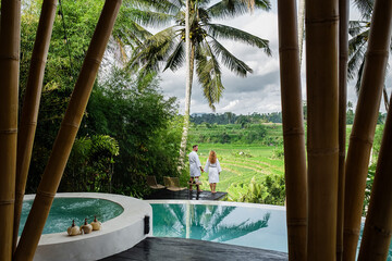 Couple at luxury villa infinity pool overlooking rice terraces in Bali, Indonesia.