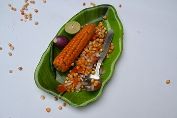 Boiled corn Chaat. Indian style corn salad that's sweet, spicy and tangy. It is mixed with chaat masala, roasted cumin powder, red chili powder, coriander leaves, onion and tomatoes. Indian snacks.