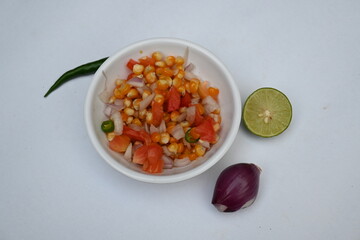 Boiled corn Chaat. Indian style corn salad that's sweet, spicy and tangy. It is mixed with chaat masala, roasted cumin powder, red chili powder, coriander leaves, onion and tomatoes. Indian snacks.