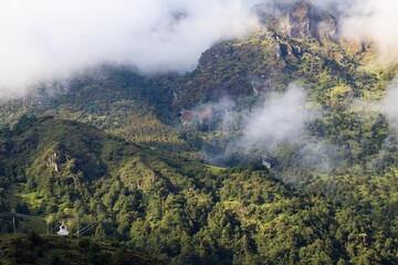 Fototapeta premium Scenic view of lush green hills and misty mountains with a small Tibetan stupa in Gyabla, Nepal, along the trail to Kanchenjunga Base Camp in the majestic Himalayas.